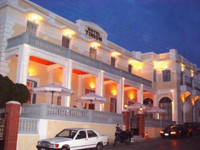 une voiture blanche garée devant un bâtiment dans l'établissement Tinion Hotel, à Tinos