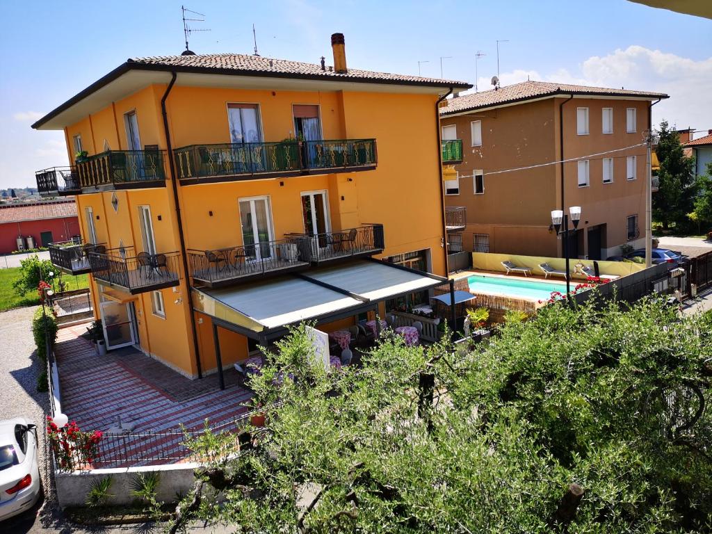 a yellow building with a swimming pool in front of it at Appartamento Alessio in Bardolino