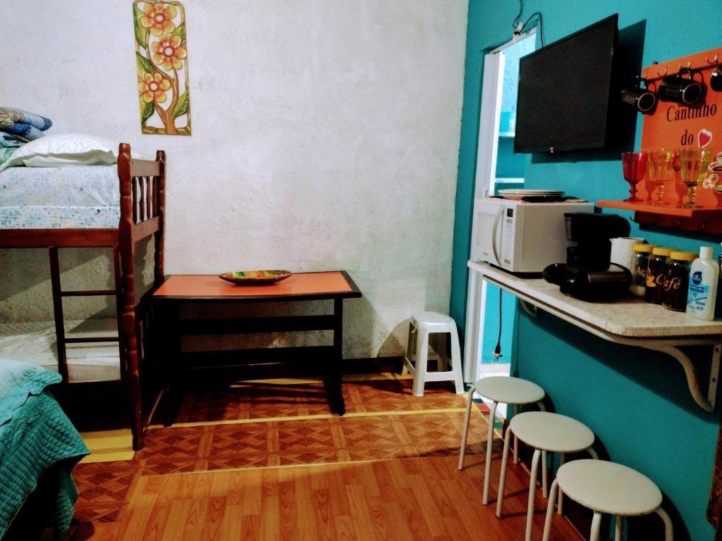 a room with a bed and a table and stools at Pertinho prahia toninhas in Ubatuba