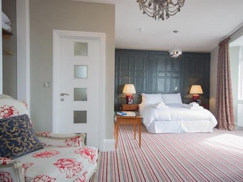 um quarto com uma cama branca e uma cadeira em Seaspray Rooms em Bexhill