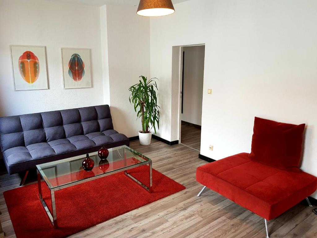 YourSweetHome في برلين: غرفة معيشة مع أريكة زرقاء وكرسي احمر