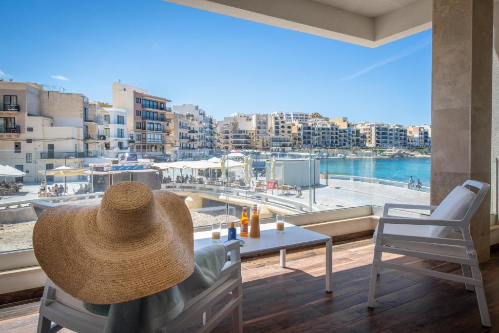 a person with a straw hat sitting on a table with a view at Electra Residence - Luxury Central Beachview Apartment in Marsalforn