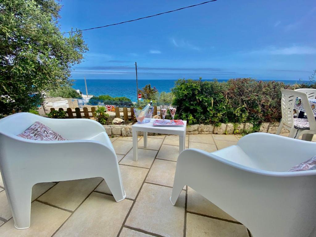 d'une terrasse avec des chaises blanches et une table donnant sur l'océan. dans l'établissement STONE Home - Sea & Landscape, à Marittima