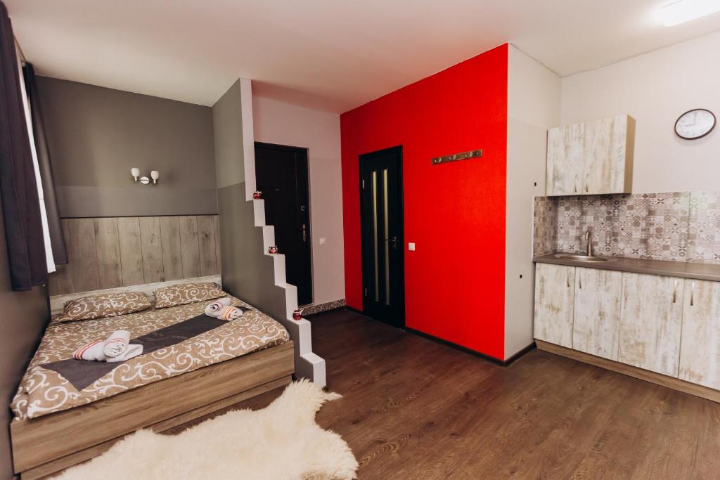a room with a bed with a red wall and stairs at Затишні Apartments in Ivano-Frankivsʼk