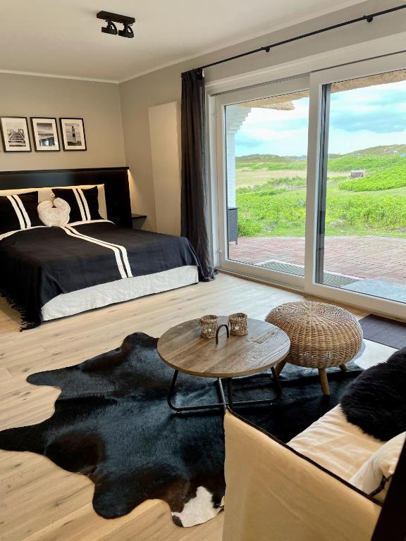 a bedroom with a bed and a table and a window at Strandhus in Rantum