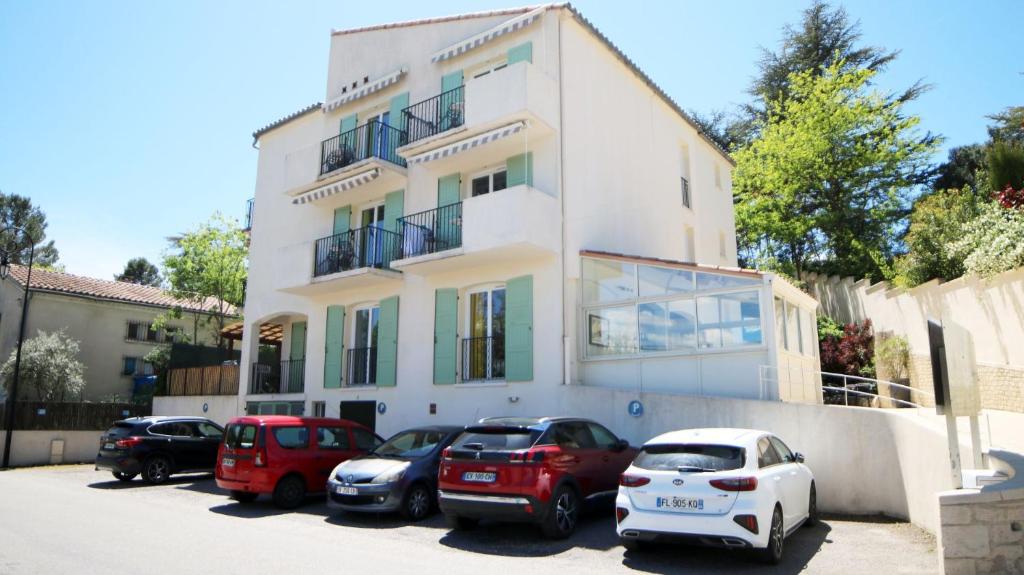 a white building with cars parked in front of it at Le Moulin du Verdon in Gréoux-les-Bains