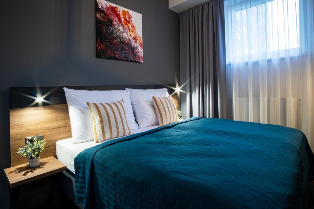 um quarto com uma cama com um cobertor azul e uma janela em Penzión Mamut Revúca em Revúca