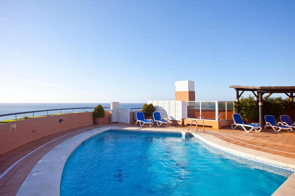 a swimming pool with chairs and the ocean in the background at Ona Princesa Playa in Marbella