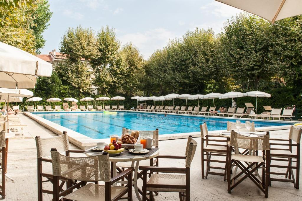 una mesa y sillas junto a una piscina en Grand Hotel Royal en Viareggio