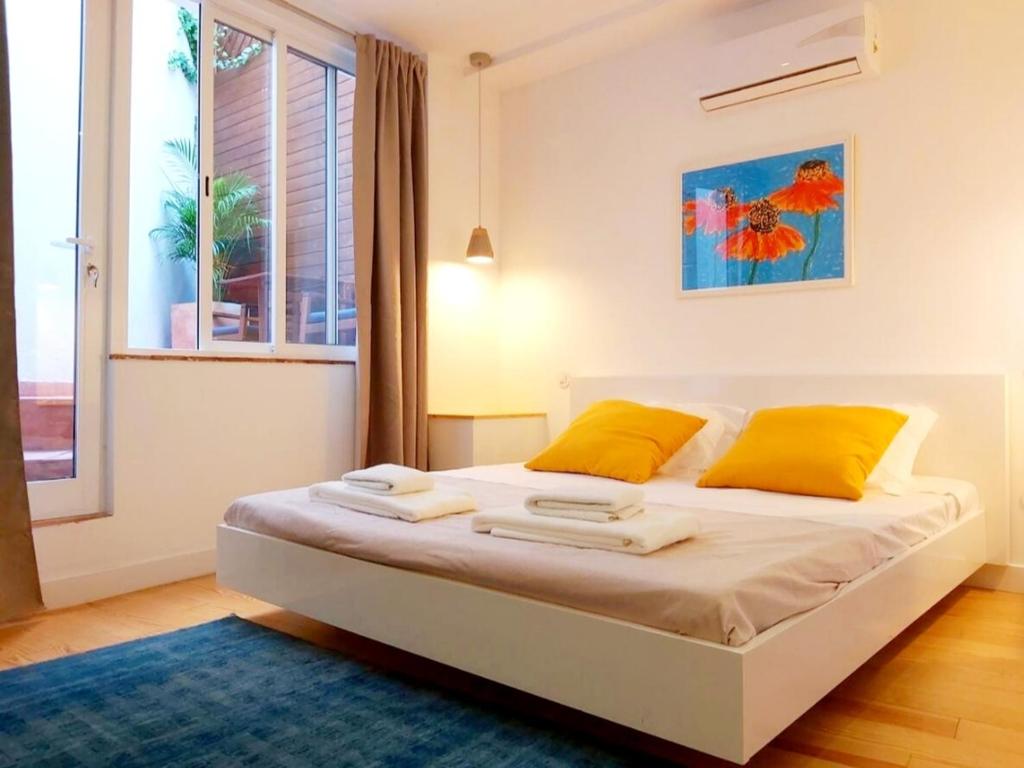 a bedroom with a bed with yellow pillows and a window at Casa do Arco by HnM in Tavira