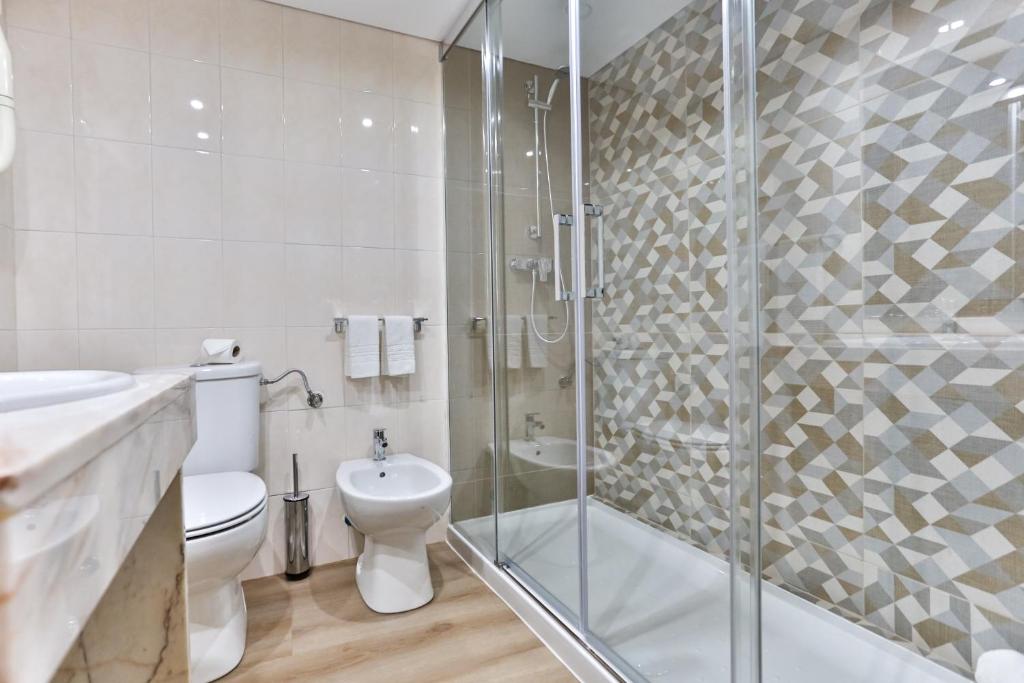 a bathroom with a toilet, sink, and shower at Hotel Arangues in Setúbal