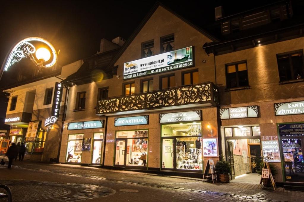 um grupo de lojas em uma rua da cidade à noite em Top Hostel Pokoje Gościnne em Zakopane