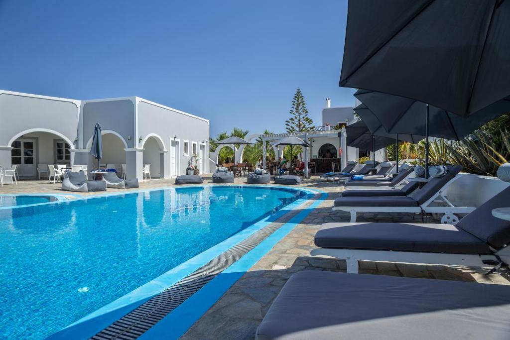 a swimming pool with lounge chairs and umbrellas at Maistros Village in Karterados