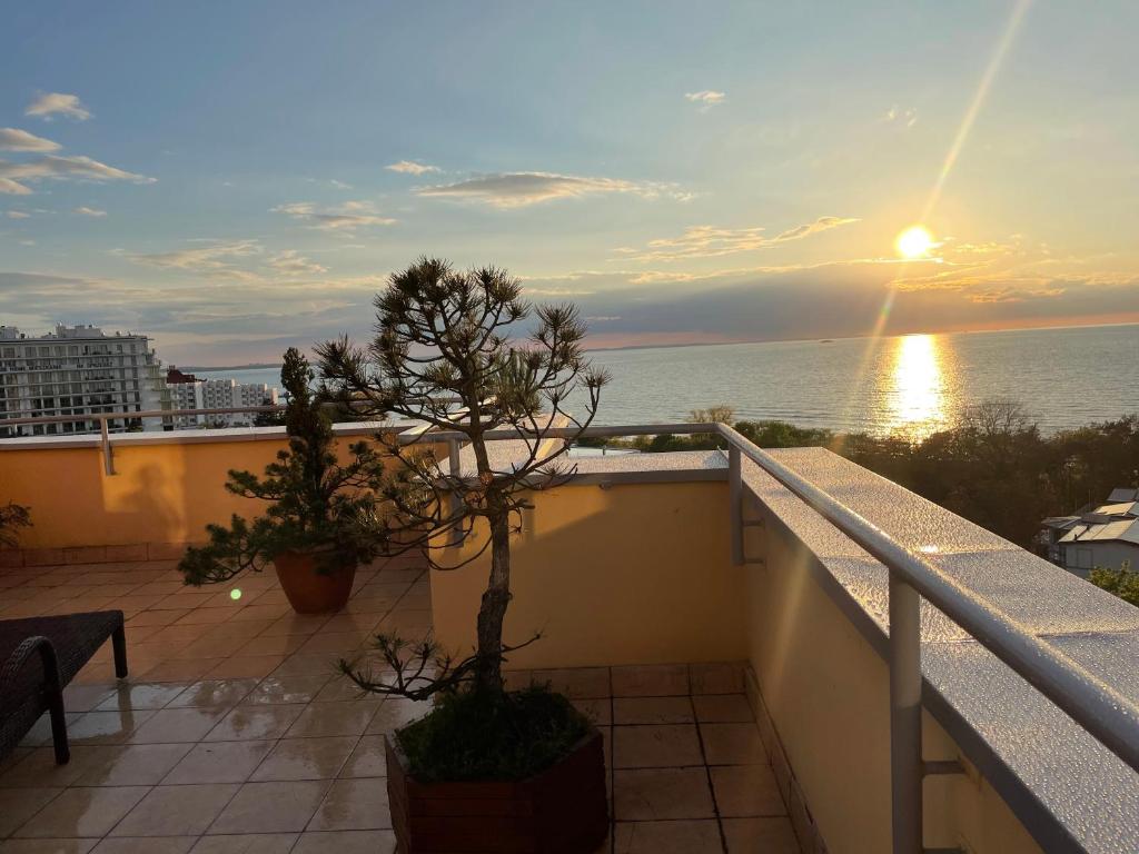 einen Balkon mit Blick auf das Meer bei Sonnenuntergang in der Unterkunft Wolin-Travel Fala apartamenty z widokiem na morze in Misdroy