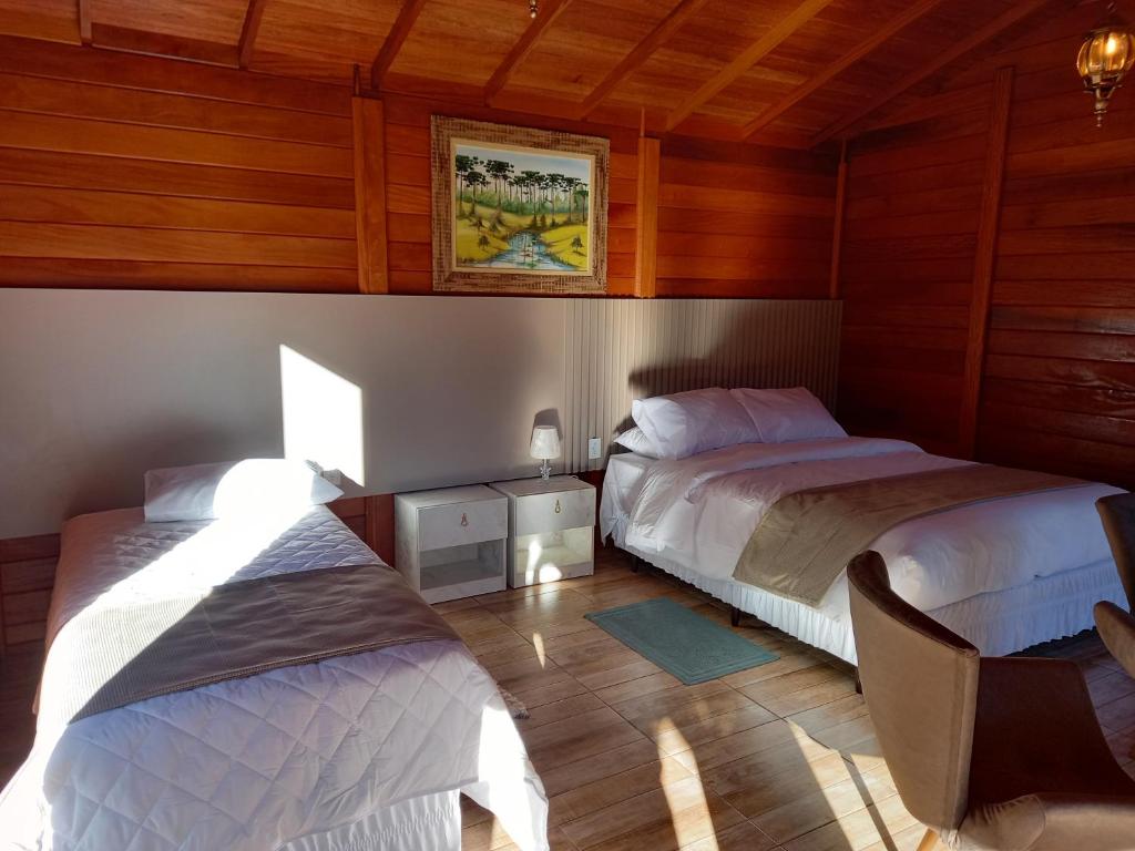 two beds in a room with wooden walls and wooden floors at Cabanas do Empório Aparados da Serra in Bom Jardim da Serra