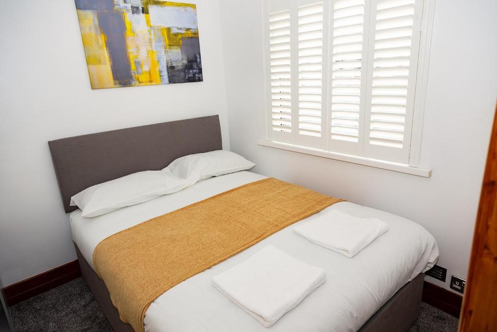 een slaapkamer met een bed met witte lakens en een raam bij Alexander Apartments Blyth in Cowpen