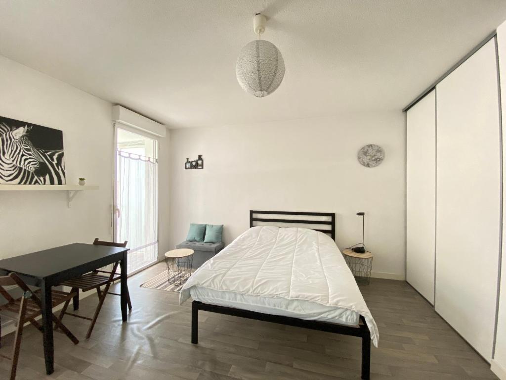Dormitorio blanco con cama y mesa en Joli studio avec terrasse près du vieux-port, en La Rochelle