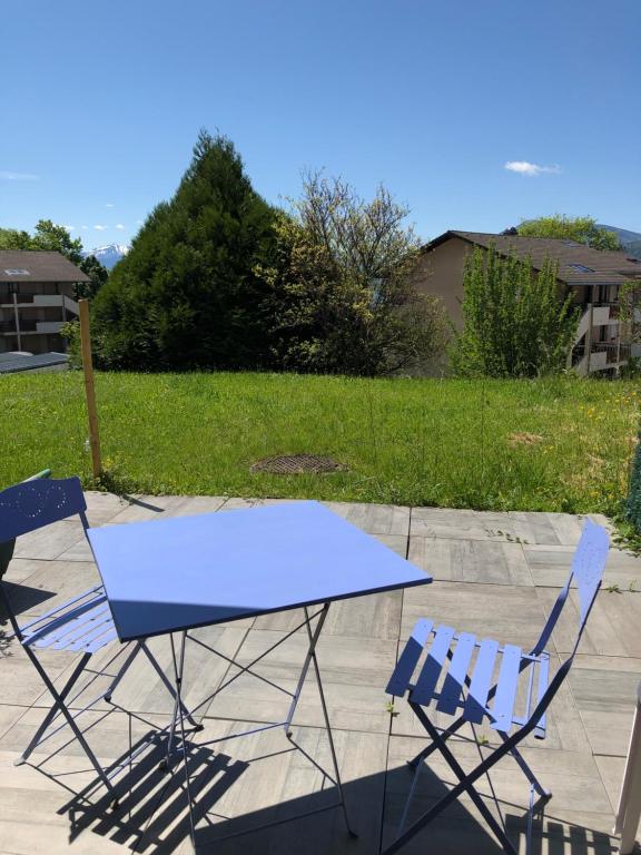 une table bleue et deux chaises sur la terrasse dans l'établissement LE CLOS du LAC STUDIO TERRASSE JARDIN et cave Vélos fermée RDC, à Annecy