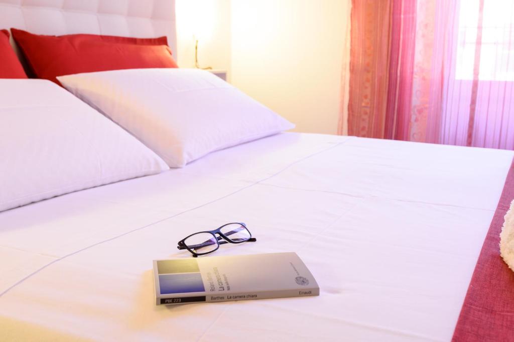 ein Paar Gläser und ein Buch auf einem Bett in der Unterkunft HouseStation in Palermo