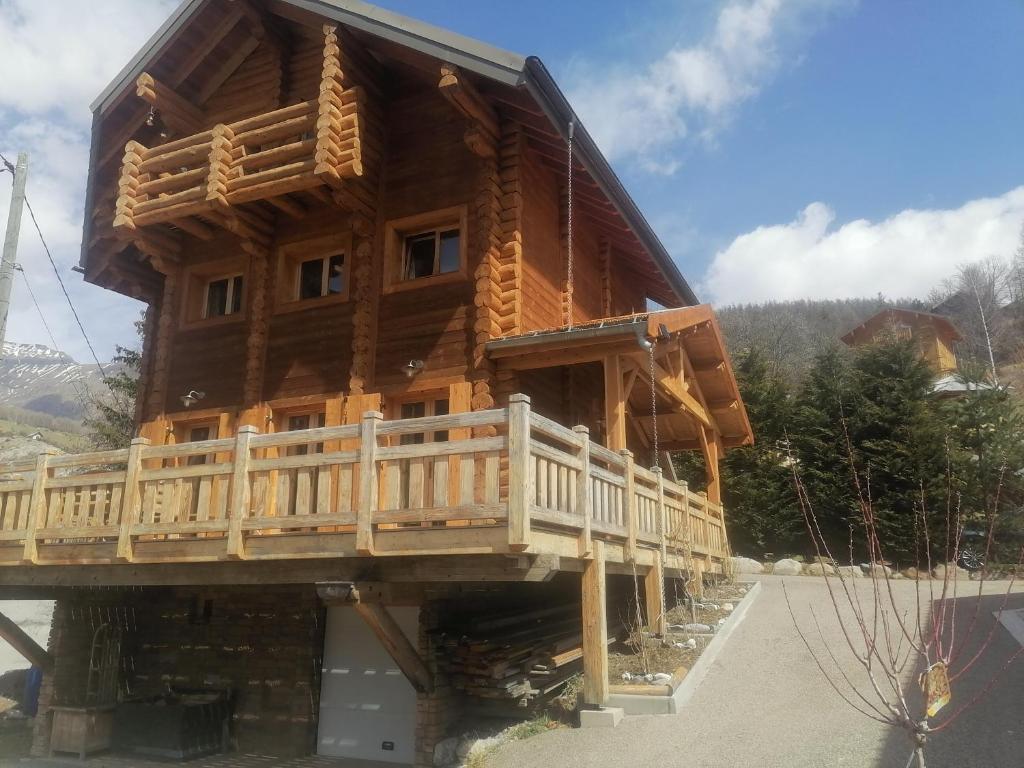 a large log cabin with a deck on the side at L'Edelweiss in Allos