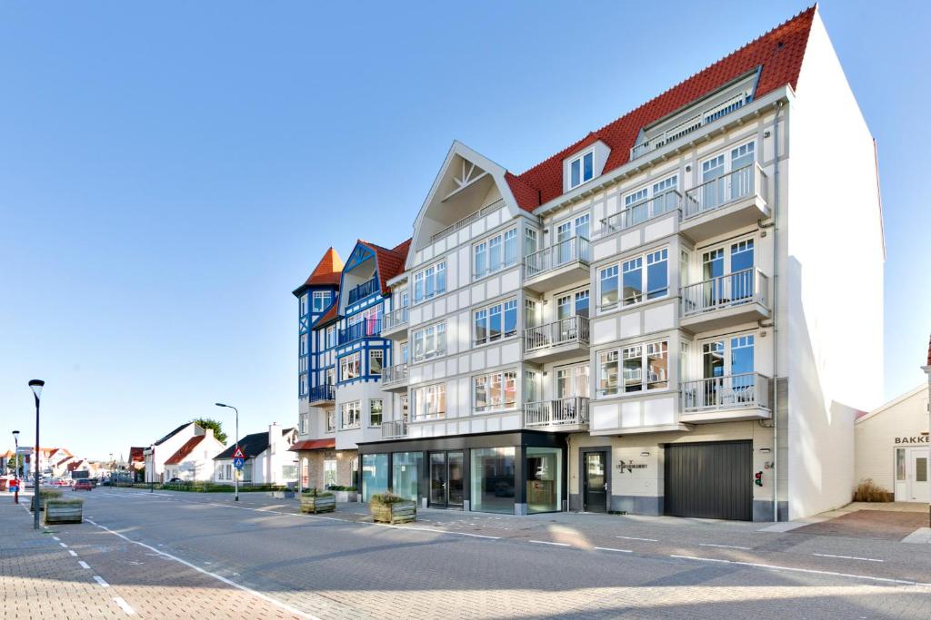 een groot wit gebouw in een stadsstraat bij Modern appartement met doorkijk op de duinen in Cadzand