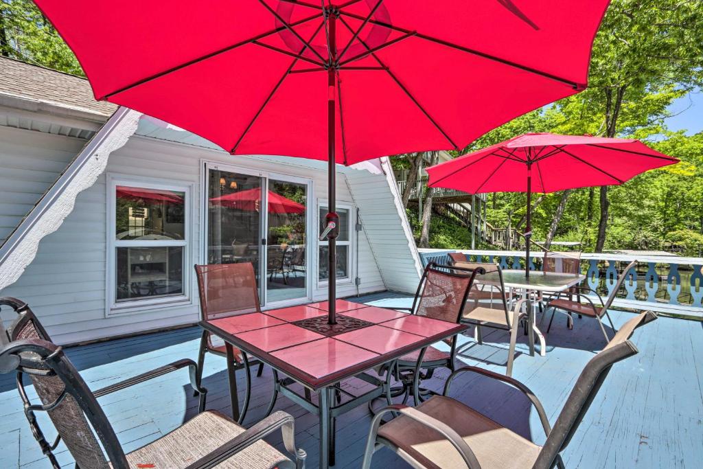 un patio con mesa y sillas con sombrillas rojas en Lakefront Rocky Mount Cabin with Dock and Kayaks!, en Rocky Mount