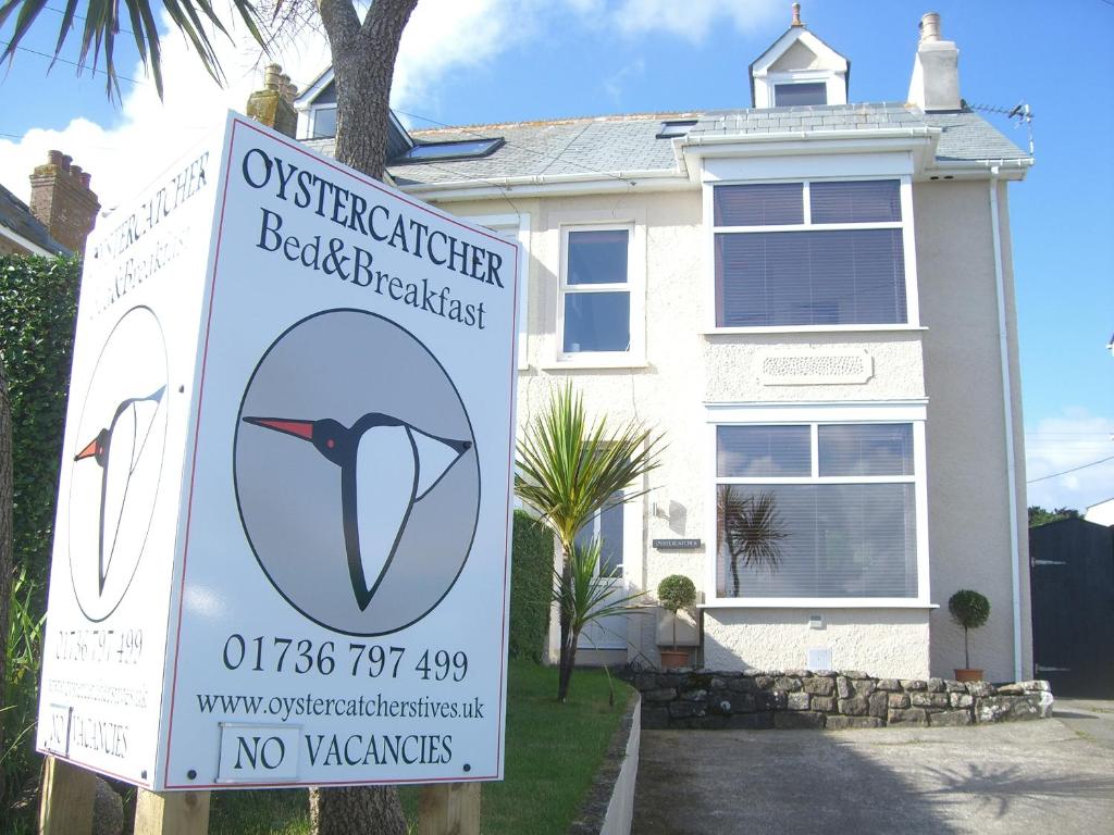 una señal frente a una casa blanca en Oystercatcher en St Ives