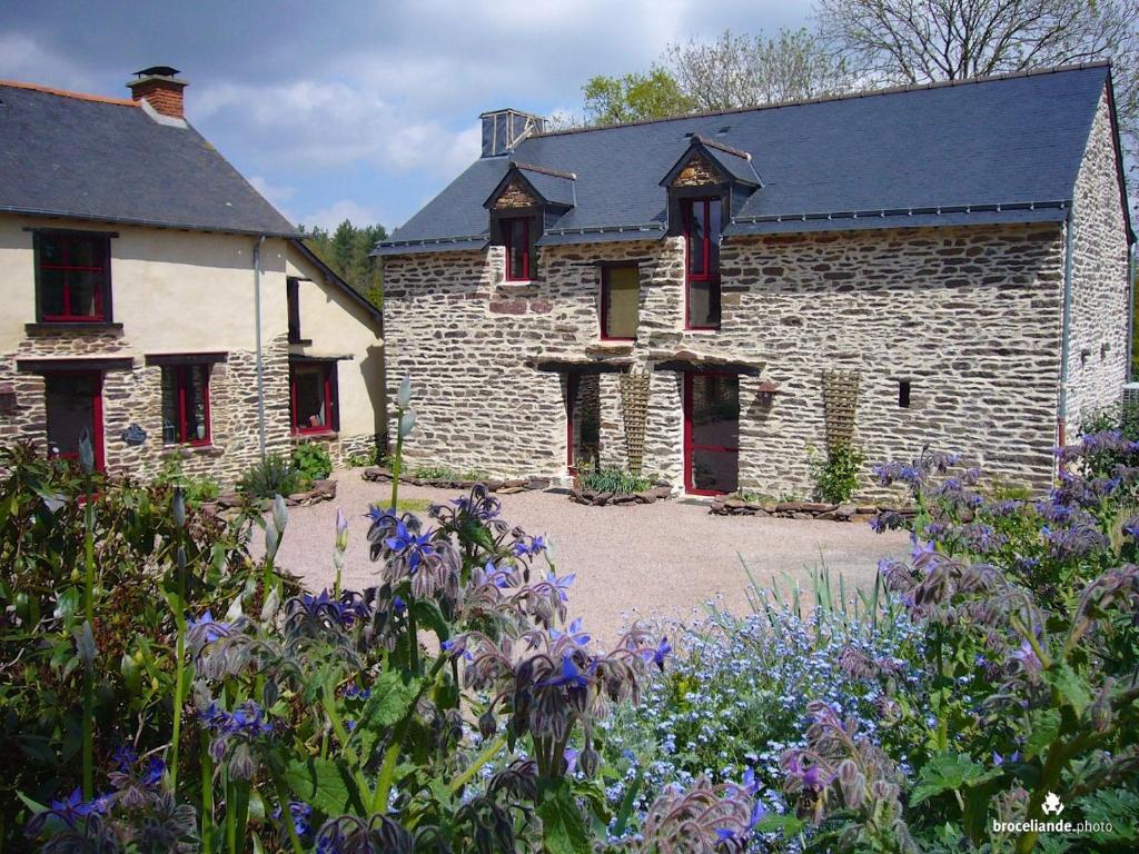 une maison en pierre avec des fleurs devant elle dans l'établissement Gîte Le Logis de l'Etang de l'Aune, à Iffendic