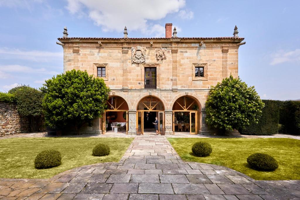 un gran edificio de ladrillo con un camino delante de él en Helguera Palacio Boutique & Antique en Santander