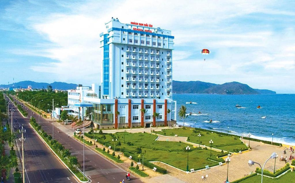 a large building next to the ocean with a kite in the sky at Seagull Hotel in Quy Nhon