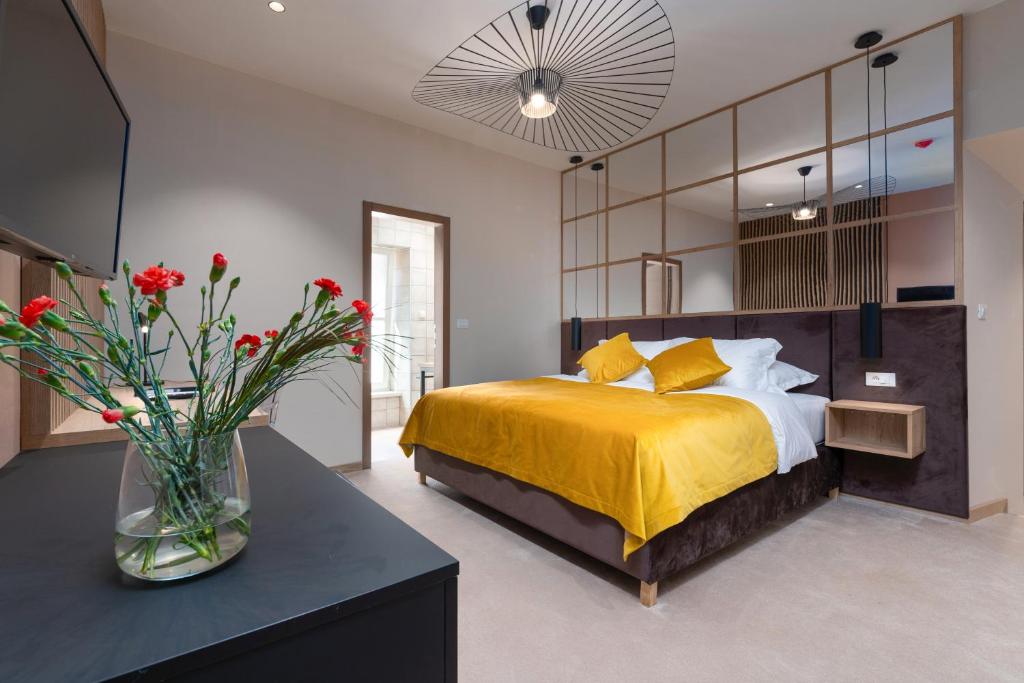a bedroom with a yellow bed and a vase of flowers at Exclusive Rooms in Casa Manzolin in Poreč