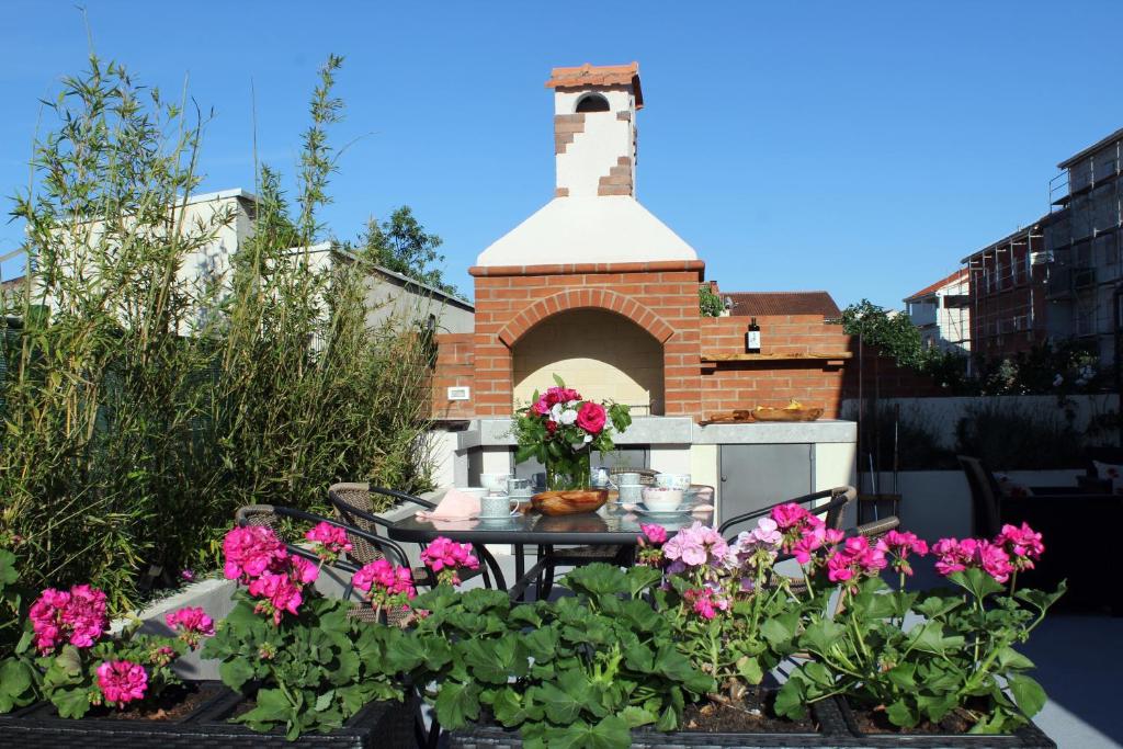 a garden with a table with flowers and a brick oven at Calypso - newly equiped, with separate entrance and parking in Supetar