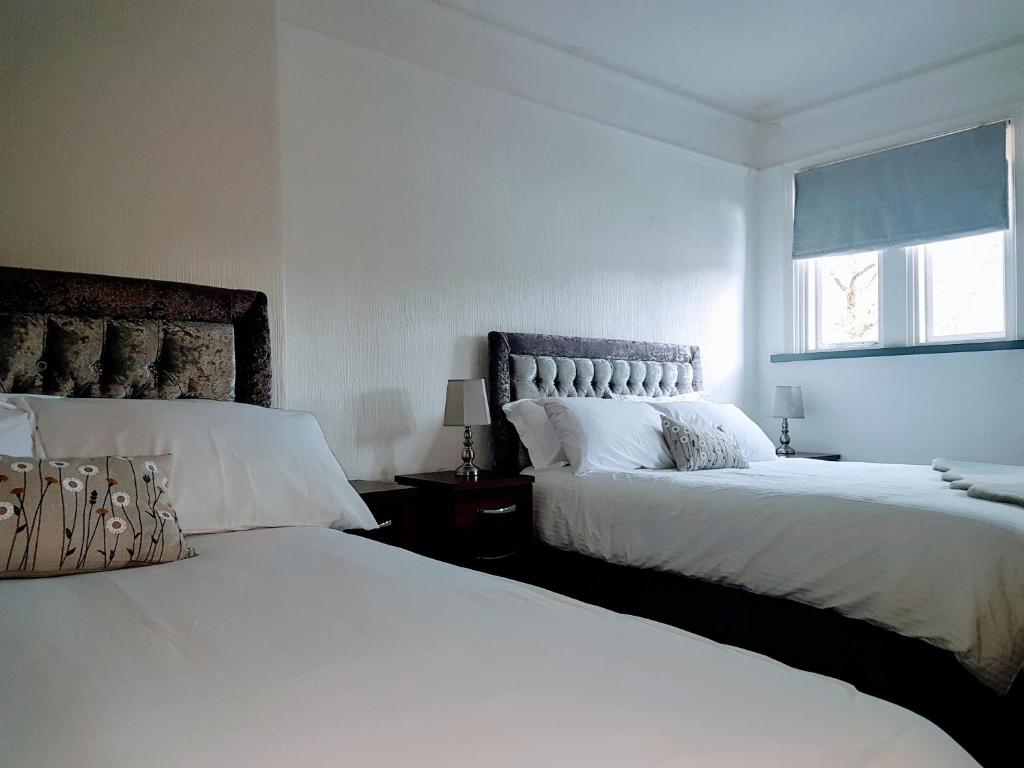 1 dormitorio blanco con 2 camas y ventana en The Vaults, en Wrexham
