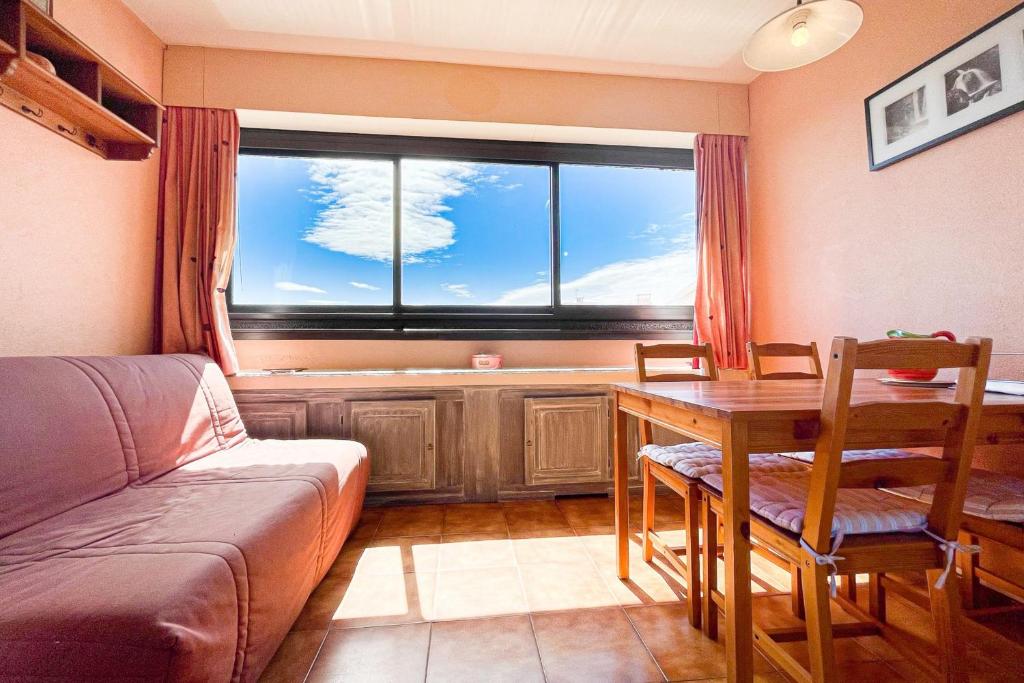 un salon avec une table et une grande fenêtre dans l'établissement Bright apartment with pool, à Fréjus