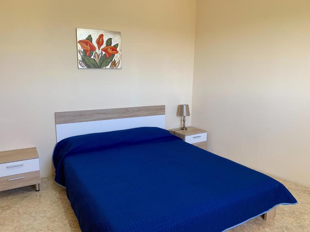 a bedroom with a blue bed and a painting on the wall at Village Apartments in Santa Luċija