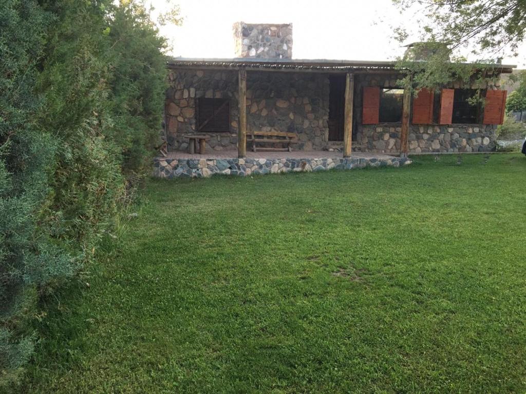a stone house with a picnic table in a yard at UTU TOCO - casa de piedra en lengua Huarpe in Potrerillos