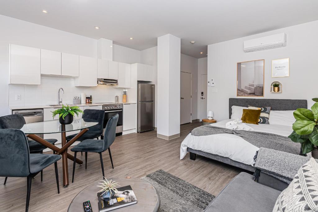 a bedroom and living room with a bed and a kitchen at New, Fresh and Luminous Studio in Le Plateau by Den Stays in Montréal
