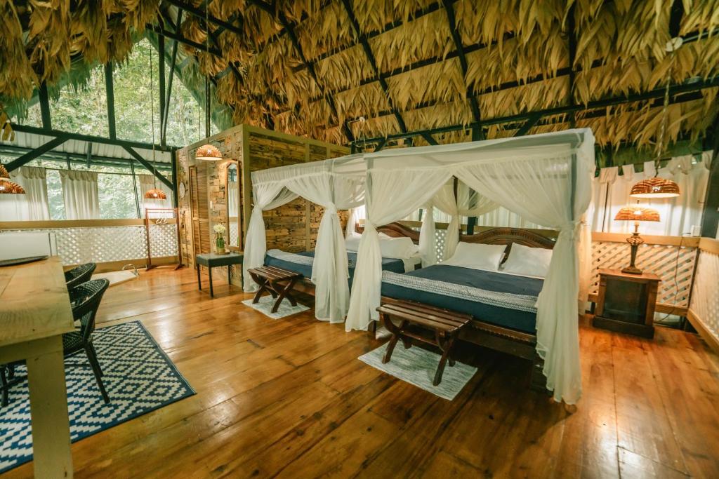 Almonds and Corals Jungle Resort في بويرتو فيجو: غرفة نوم بسرير مظلة وأرضية خشبية
