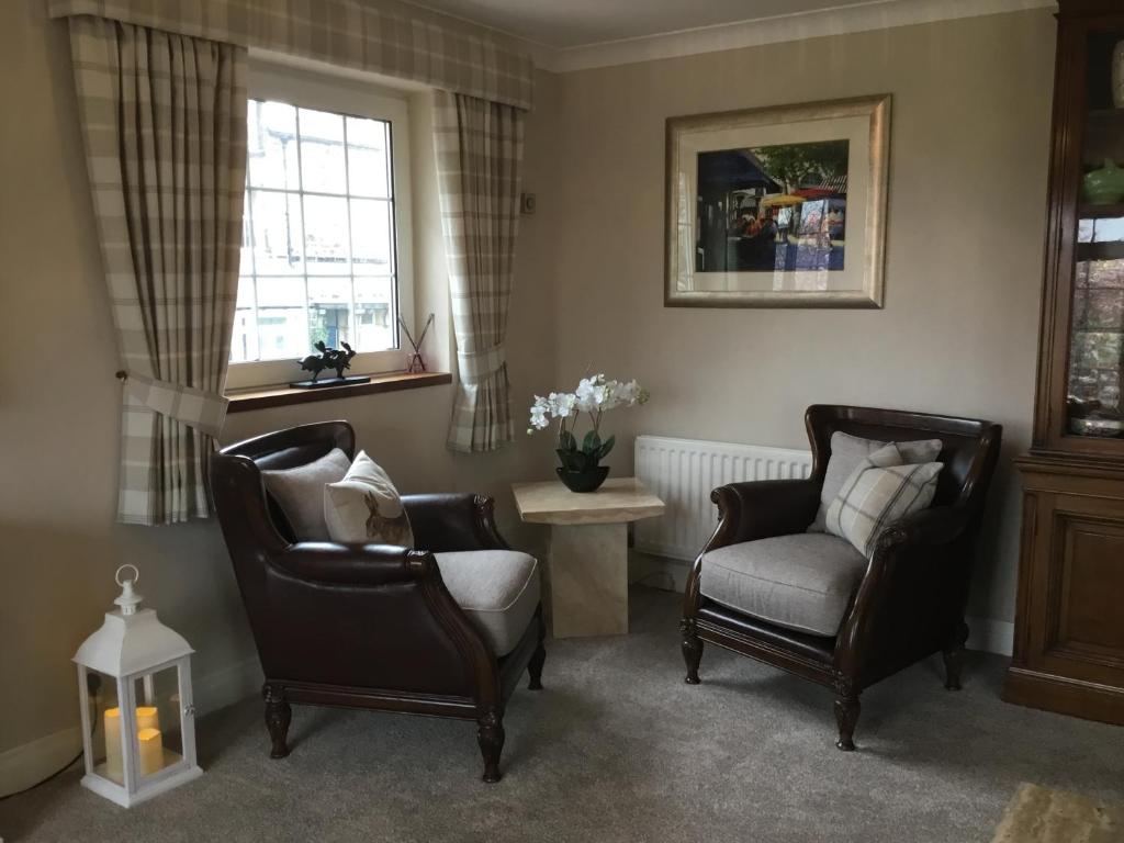 a living room with two chairs and a table and window at Westlea Guest House in Alnmouth