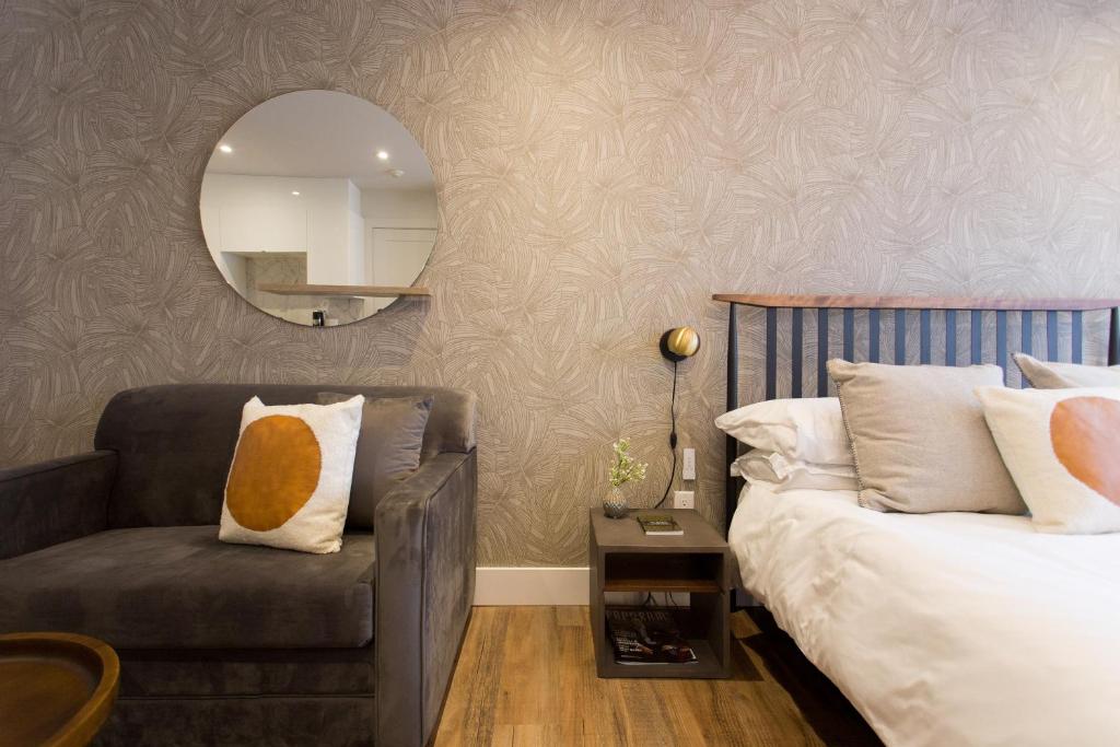 1 dormitorio con cama, silla y espejo en Scandinavian Studio with Full Kitchen and Bath by Den Stays, en Montreal