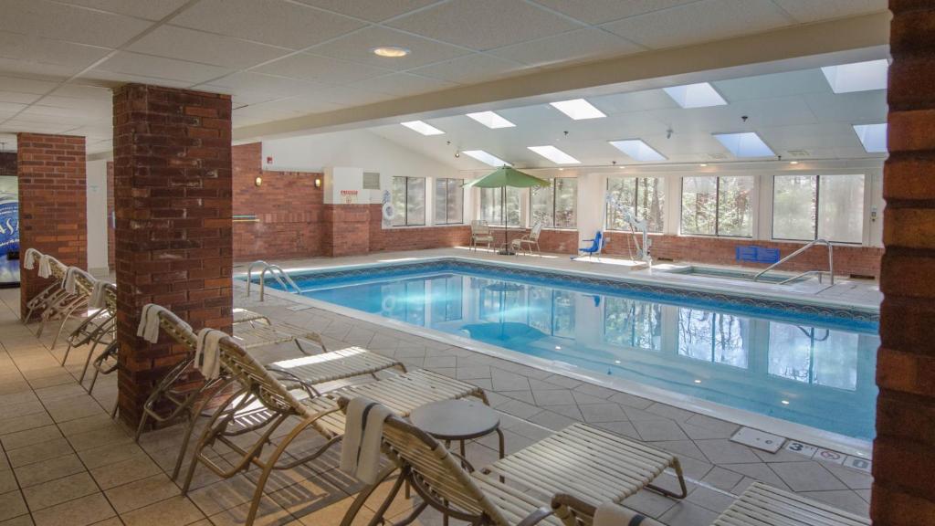 uma grande piscina com cadeiras e uma mesa num edifício em Holiday Inn Express South Burlington, an IHG Hotel em Burlington