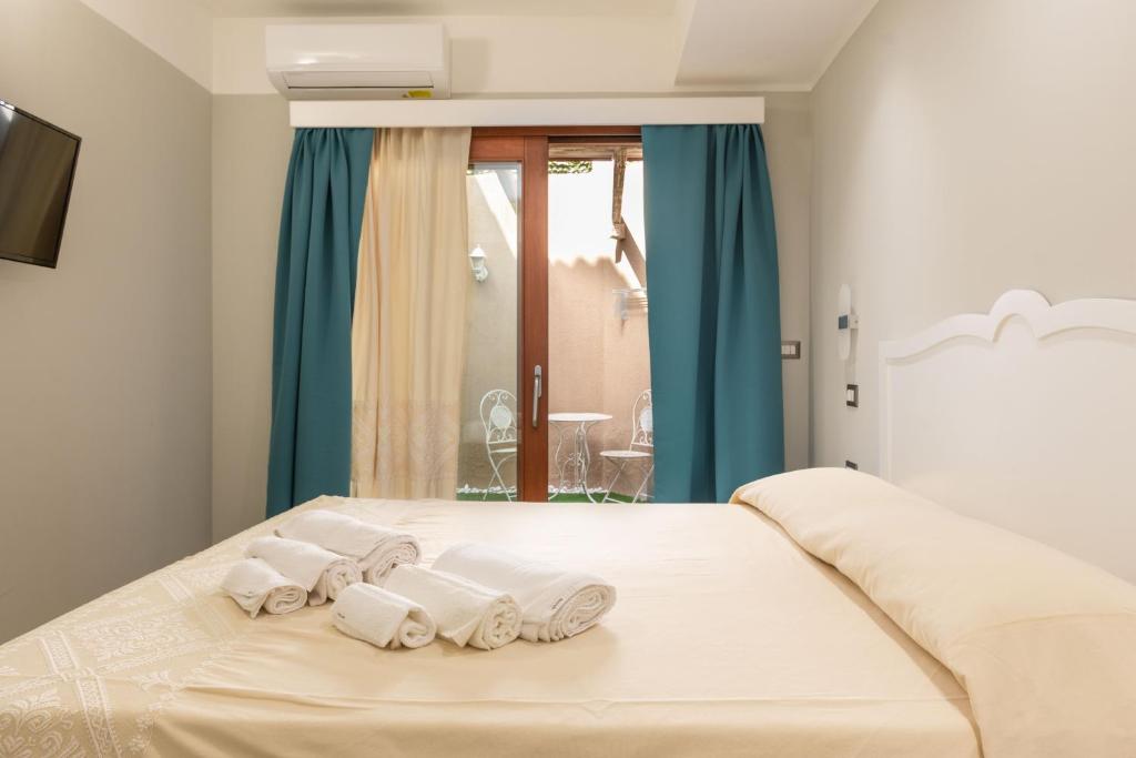 un letto bianco con quattro asciugamani sopra di Domu Ajaju Guest House a Villasimius