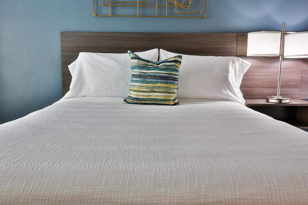 a large white bed with a striped pillow on it at The Chalet in St. George