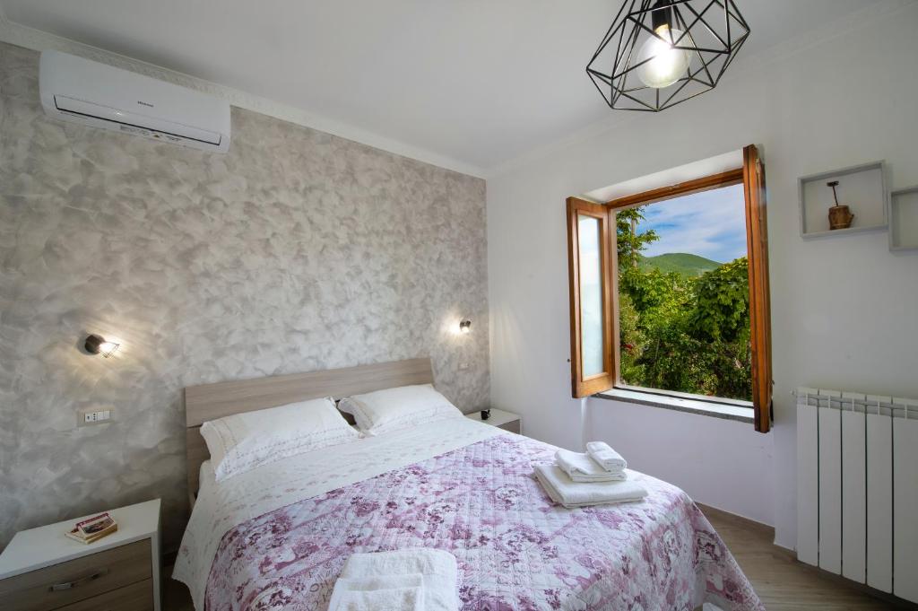 a bedroom with a large bed and a window at HedèraRooms in Agerola