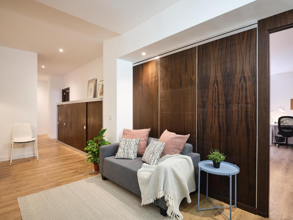 マドリードにあるMy City Home - Fantastic apartament at Moncloa for studentsのソファ付きのリビングルーム、木製の壁