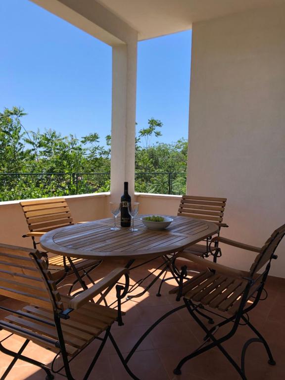 una mesa y sillas en un porche con una botella de vino en Apartments Mira, en Trogir
