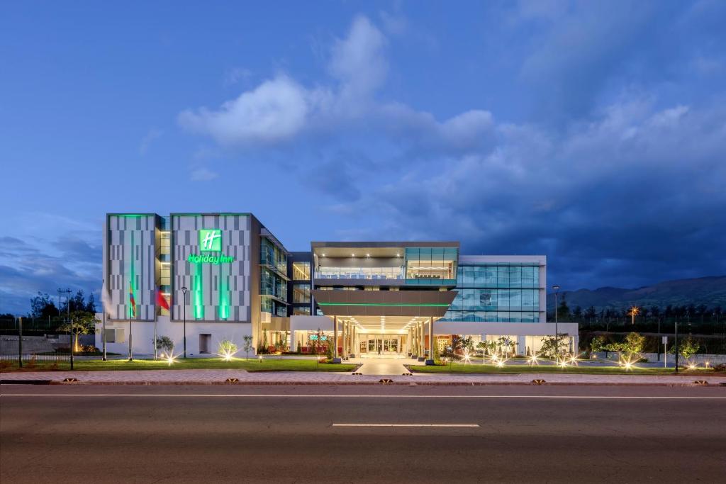 un gran edificio de oficinas con una fachada iluminada por la noche en Holiday Inn - Quito Airport, an IHG Hotel, en Tababela