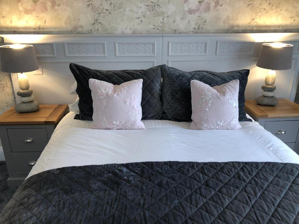 a bedroom with a large bed with pillows and two lamps at Westlea Guest House in Alnmouth