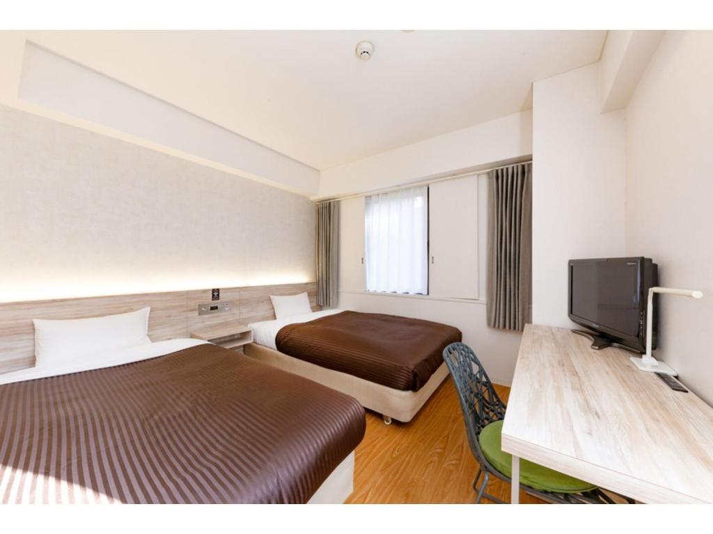 a hotel room with two beds and a flat screen tv at The One Five Fukuoka Tenjin - Vacation STAY 40121v in Fukuoka