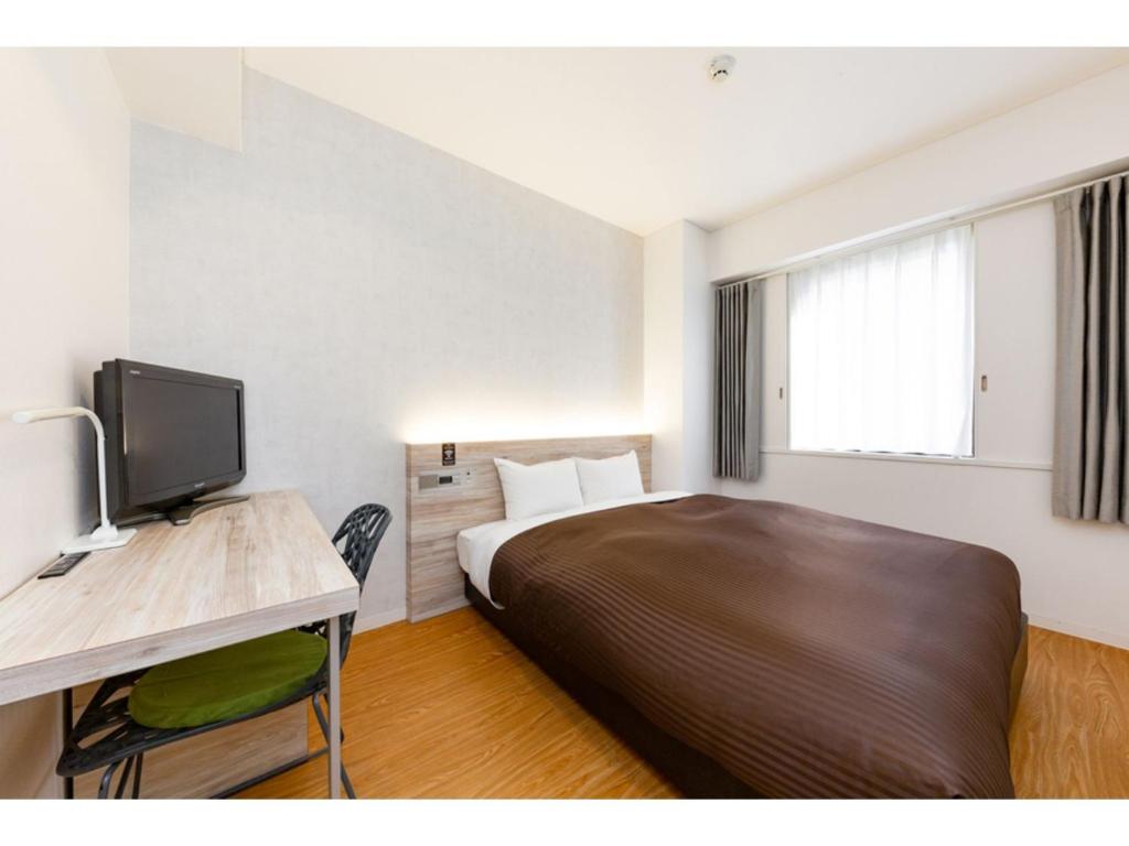 a hotel room with a bed and a desk with a television at The One Five Fukuoka Tenjin - Vacation STAY 40114v in Fukuoka